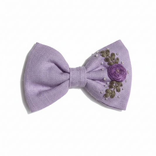 Hand-embroidered lilac hair bow with delicate details, perfect for girls' accessories and special occasions.